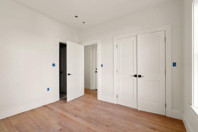 unfurnished bedroom with light wood-type flooring, baseboards, and a closet