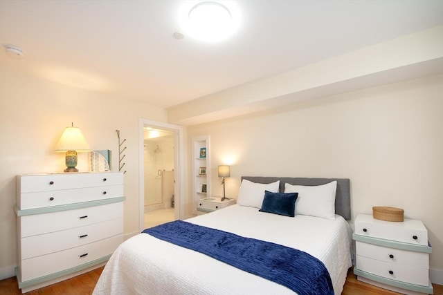 bedroom featuring light wood-type flooring and ensuite bath