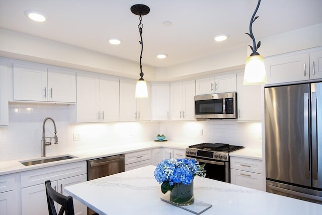 kitchen with appliances with stainless steel finishes, white cabinetry, hanging light fixtures, and sink