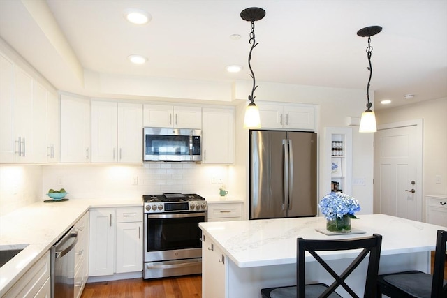 kitchen featuring pendant lighting, backsplash, dark hardwood / wood-style floors, appliances with stainless steel finishes, and white cabinetry