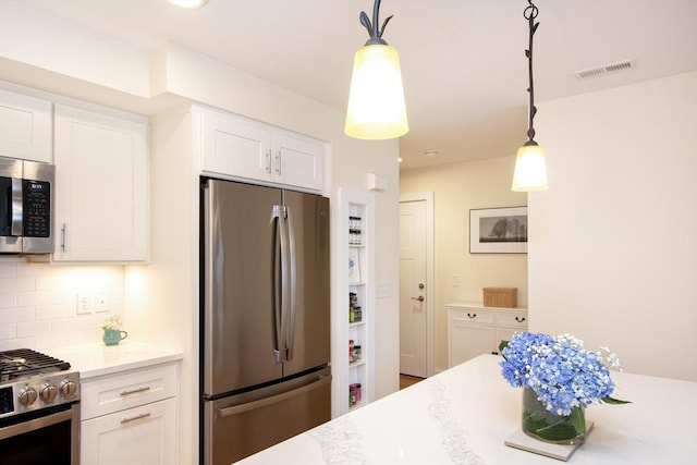 kitchen with backsplash, white cabinetry, hanging light fixtures, and appliances with stainless steel finishes