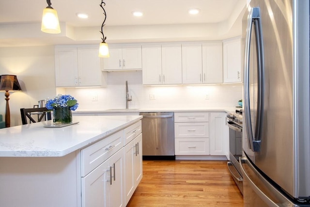 kitchen featuring white cabinets, decorative light fixtures, and appliances with stainless steel finishes