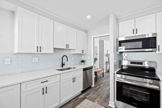 kitchen featuring light stone counters, dark wood-type flooring, a sink, white cabinetry, and appliances with stainless steel finishes