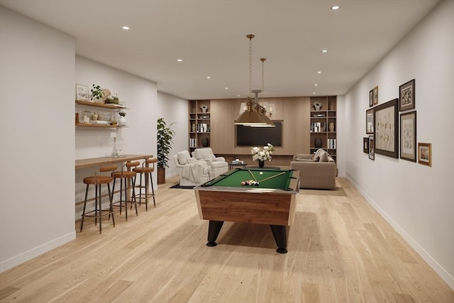 recreation room with light hardwood / wood-style floors, pool table, bar, and built in shelves