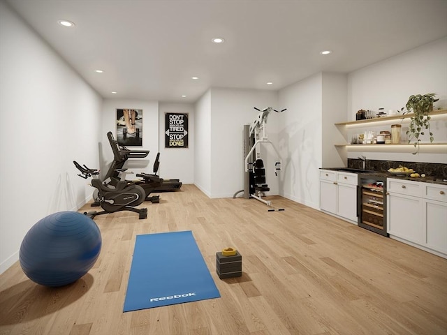 exercise area with light hardwood / wood-style floors, wine cooler, and indoor bar