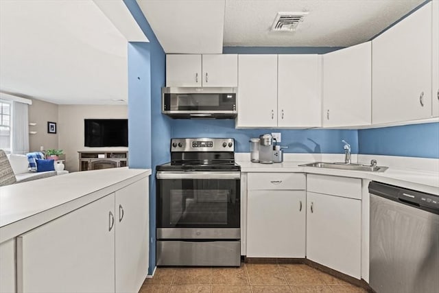 kitchen featuring sink, light tile patterned flooring, white cabinets, and appliances with stainless steel finishes