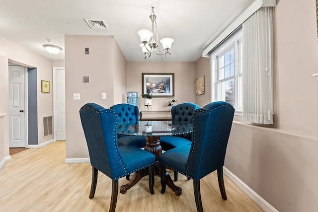 dining space with hardwood / wood-style floors and a chandelier