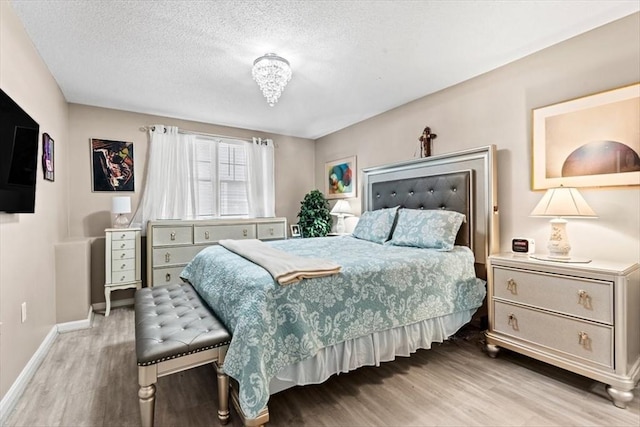 bedroom featuring a textured ceiling and light hardwood / wood-style flooring