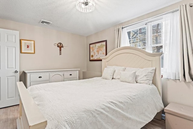 bedroom with light hardwood / wood-style flooring and a textured ceiling