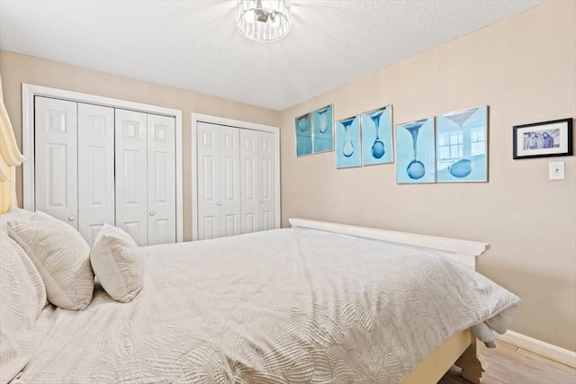 bedroom with multiple closets and light hardwood / wood-style flooring