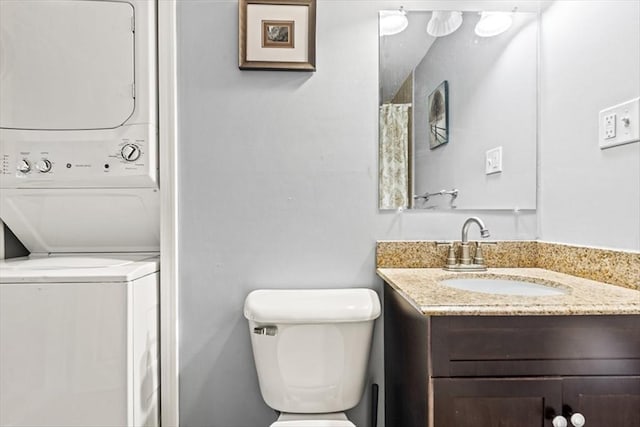 bathroom with stacked washer and clothes dryer, toilet, and vanity