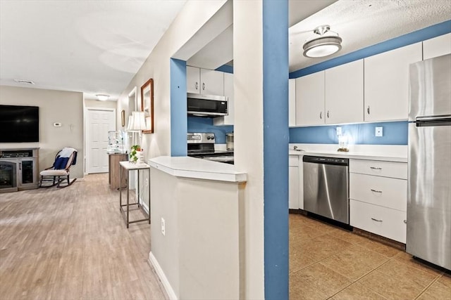 kitchen with white cabinetry, appliances with stainless steel finishes, and light wood-type flooring