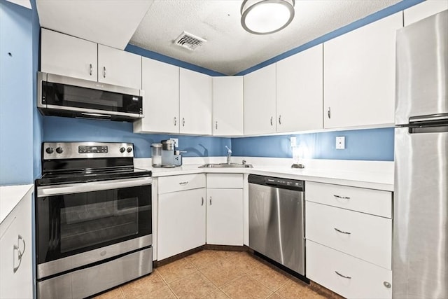 kitchen featuring white cabinetry, stainless steel appliances, light tile patterned flooring, and sink