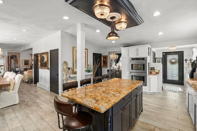 6 Rio, Gloucester, MA 01930 - kitchen with double oven, light wood-style floors, white cabinetry, a kitchen breakfast bar, and recessed lighting