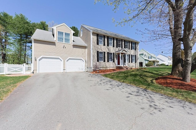 colonial inspired home featuring aphalt driveway, fence, and a front yard