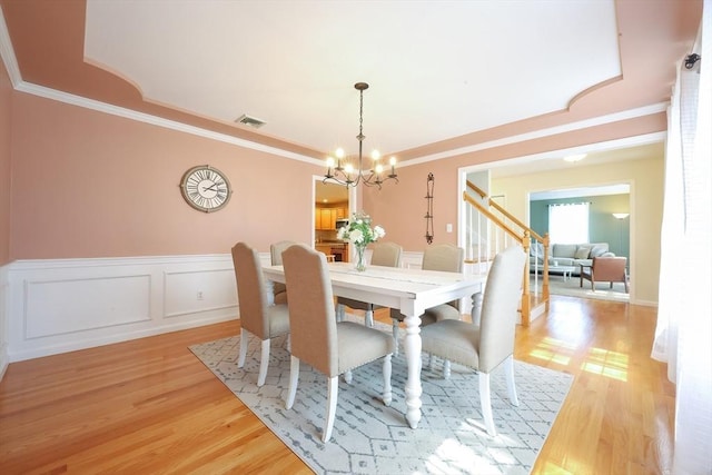 dining room with crown molding, a notable chandelier, light wood-style flooring, and visible vents