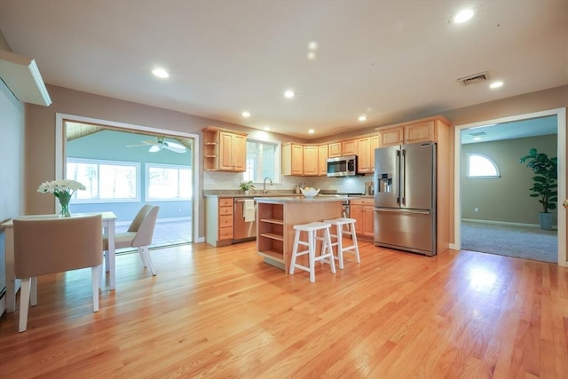 kitchen with light brown cabinetry, open shelves, a center island, stainless steel appliances, and visible vents