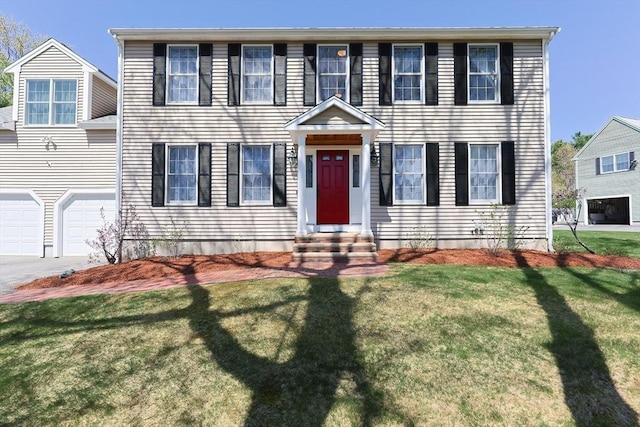 colonial house with entry steps, an attached garage, driveway, and a front lawn