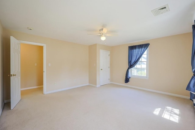 spare room featuring baseboards, ceiling fan, light carpet, and visible vents