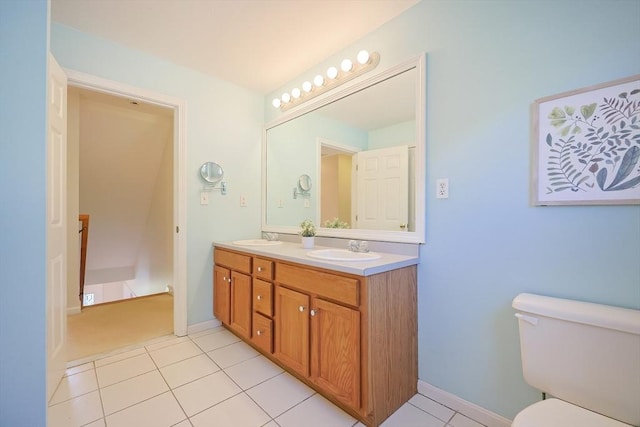 bathroom with a sink, tile patterned floors, toilet, and double vanity
