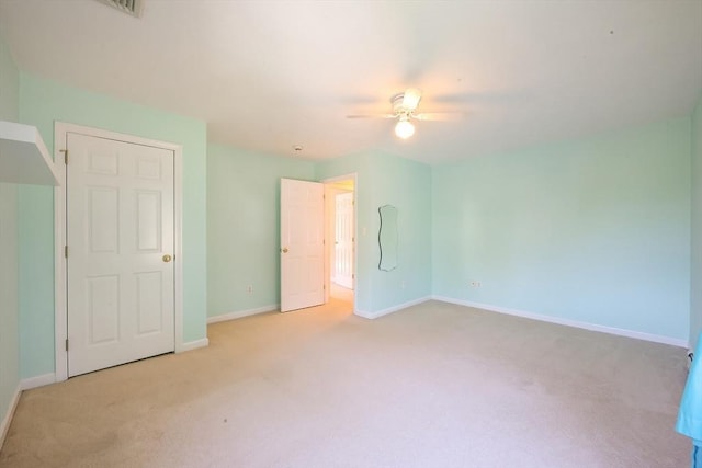 unfurnished bedroom featuring baseboards, light carpet, and a ceiling fan