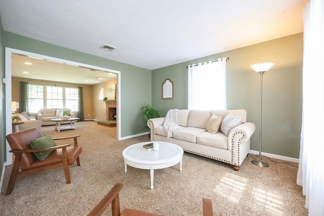 living area featuring visible vents, a brick fireplace, carpet, baseboards, and a baseboard heating unit