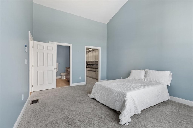 carpeted bedroom with high vaulted ceiling, ensuite bath, and a spacious closet