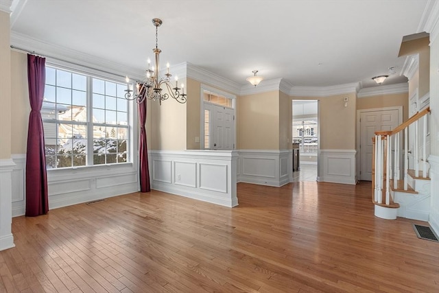 unfurnished dining area featuring a chandelier, ornamental molding, and light hardwood / wood-style floors