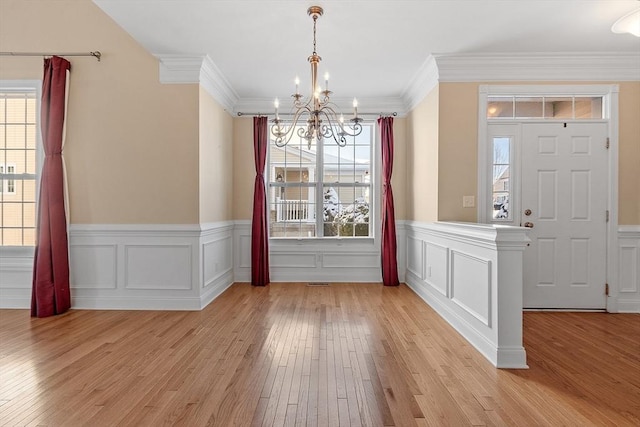 entrance foyer featuring light hardwood / wood-style floors, ornamental molding, and a notable chandelier