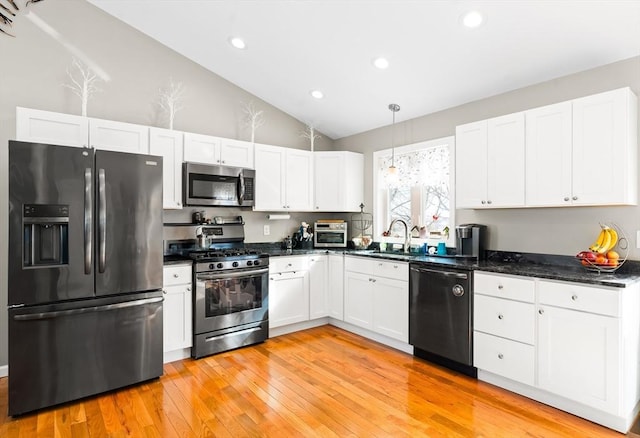 kitchen featuring lofted ceiling, a sink, white cabinetry, black appliances, and decorative light fixtures