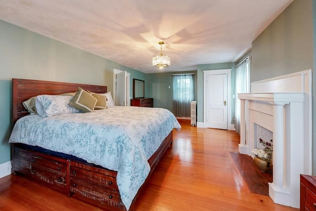 19 Orlando Ave, Winthrop, MA 02152 - bedroom with radiator heating unit, wood finished floors, a chandelier, a fireplace with flush hearth, and baseboards