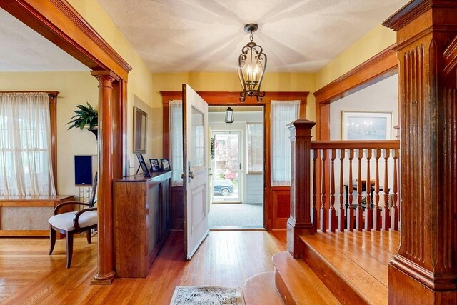 19 Orlando Ave, Winthrop, MA 02152 - entryway with light wood finished floors, a chandelier, a wainscoted wall, and ornate columns