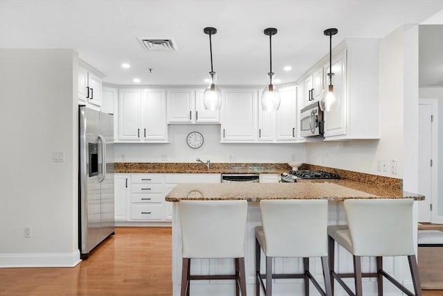 95 Conant St Unit 404, Concord, MA 01742 - kitchen with appliances with stainless steel finishes, a peninsula, recessed lighting, baseboards, and stone countertops