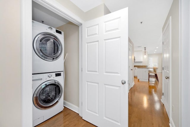 95 Conant St Unit 404, Concord, MA 01742 - laundry room featuring stacked washing machine and dryer, light wood-style flooring, and baseboards