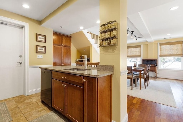 bar with light wood-style floors, a sink, dishwasher, baseboards, and stairs