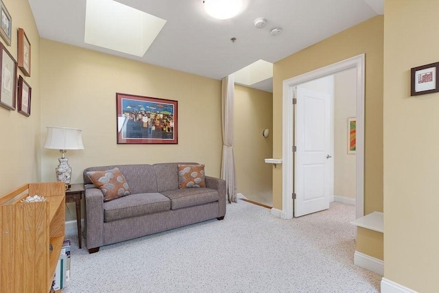 living room with light carpet, a skylight, and baseboards