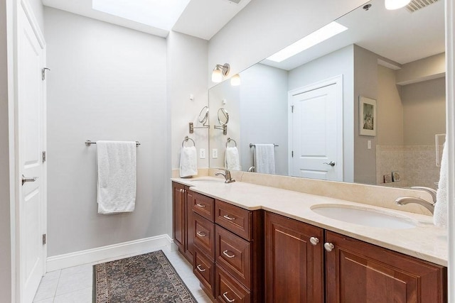 full bathroom featuring double vanity, a skylight, a sink, and tile patterned floors