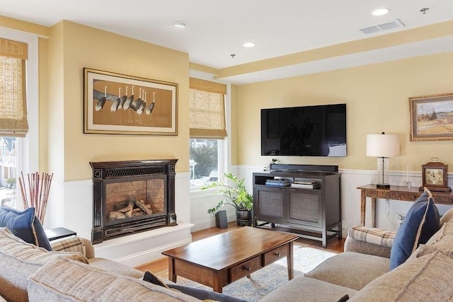 living area with light wood-type flooring, visible vents, a fireplace with raised hearth, and recessed lighting