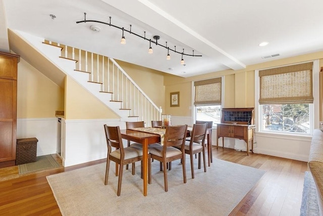 dining space featuring rail lighting, visible vents, light wood-style floors, baseboards, and stairs