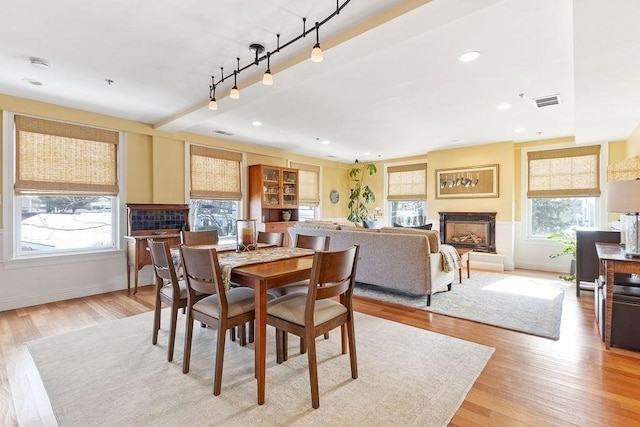 dining area with light wood finished floors, baseboards, visible vents, a fireplace, and recessed lighting