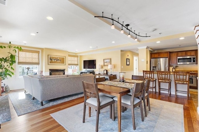 dining room featuring light wood-type flooring, rail lighting, a fireplace, and recessed lighting