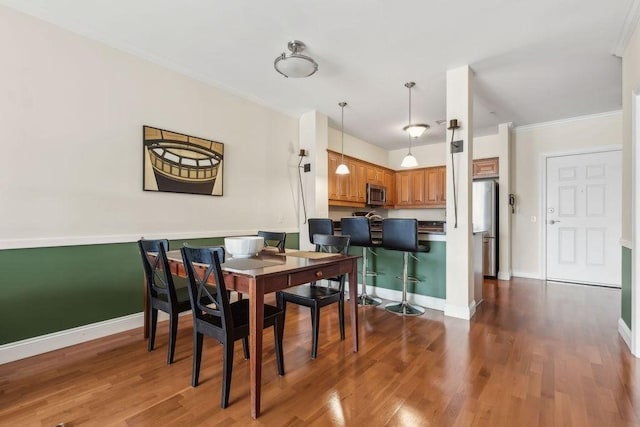 dining space with wood finished floors, crown molding, and baseboards