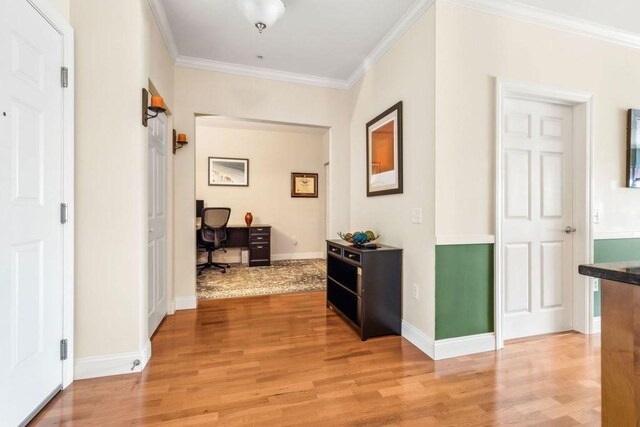 corridor with an office area, crown molding, light wood-style floors, and baseboards