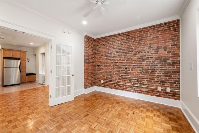 unfurnished room featuring brick wall, baseboards, ceiling fan, and crown molding
