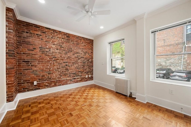unfurnished room featuring radiator, brick wall, baseboards, ornamental molding, and a ceiling fan