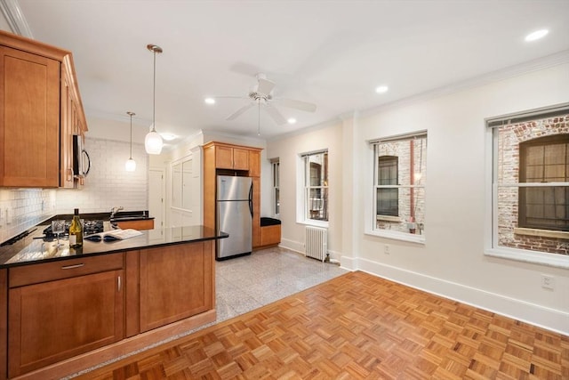 kitchen featuring stainless steel appliances, radiator heating unit, a ceiling fan, dark countertops, and tasteful backsplash