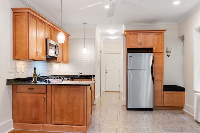 kitchen with appliances with stainless steel finishes, a sink, brown cabinets, and ornamental molding