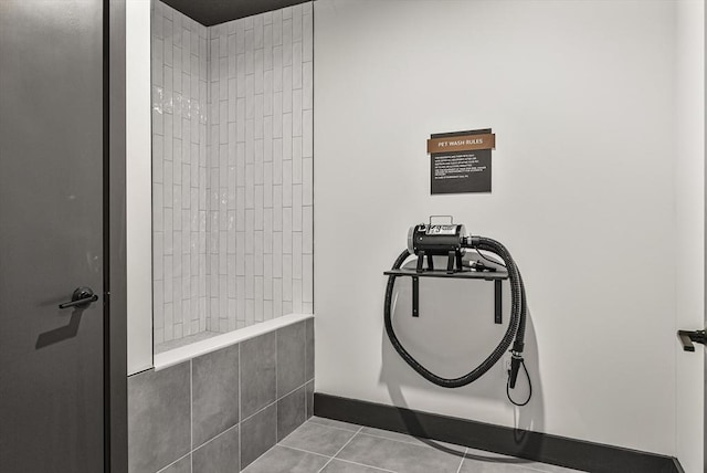 full bath featuring baseboards, tiled shower, and tile patterned flooring