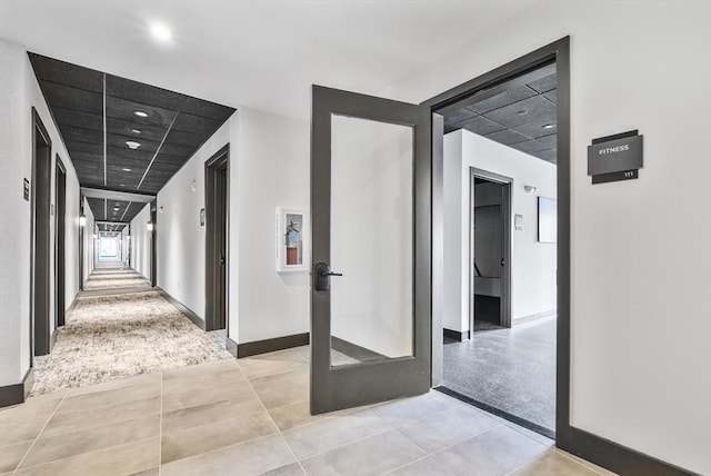 corridor with recessed lighting, baseboards, and light tile patterned floors