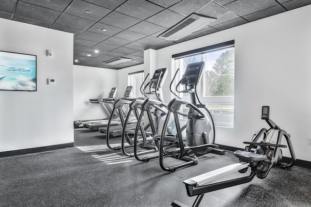 gym featuring baseboards, a drop ceiling, and visible vents